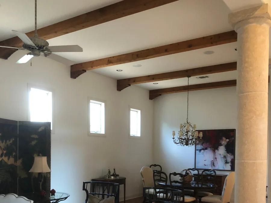 Great room with stained wood ceiling beams, smooth painted ceiling and walls, clerestory windows and a limestone column